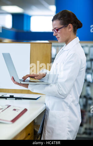 Pharmacien using laptop in pharmacy Banque D'Images