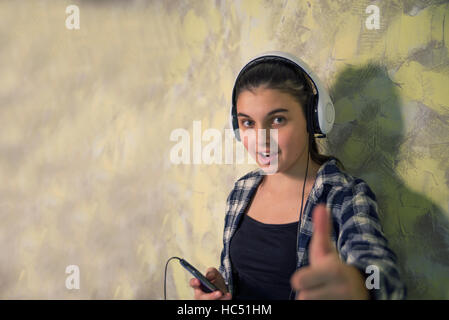 Jolie fille en chemise à carreaux avec casque et cell phone Banque D'Images