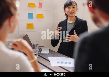 Businesswoman standing par un mur avec des notes autocollantes menant une présentation d'affaires. Female executive mettre ses idées sur les notes adhésives lors d'une pres Banque D'Images