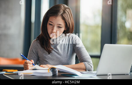 Coup de jeune femme en prenant des notes dans un agenda. La préparation des étudiants de l'université féminine note pour l'examen à la bibliothèque. Banque D'Images