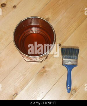 Pinceau vernis avec de l'étain peut sur plancher en bois Banque D'Images