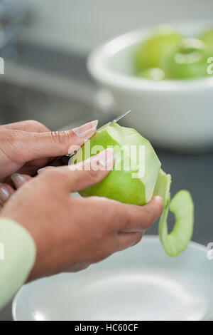 Les mains des femmes une desquamation de la peau d'une pomme verte à l'aide d'un couteau d'office Banque D'Images