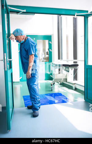 Chirurgien triste appuyé contre la porte en verre Banque D'Images