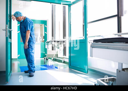 Chirurgien triste appuyé contre la porte en verre Banque D'Images