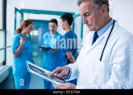 Doctor standing in corridor examining x-ray Banque D'Images