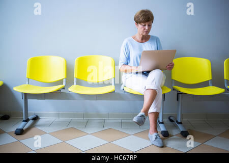 Patient assis avec rapport dans une salle d'attente Banque D'Images