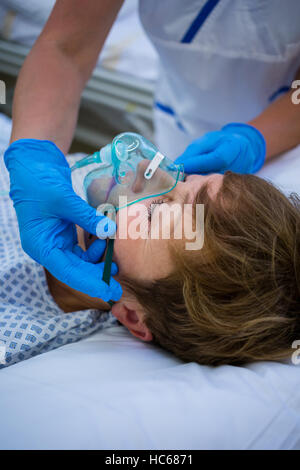 Placer l'infirmière d'un masque à oxygène sur le visage d'un patient Banque D'Images