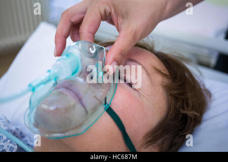 Placer l'infirmière d'un masque à oxygène sur le visage d'un patient Banque D'Images