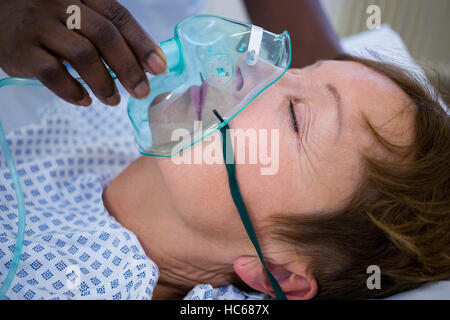 Placer l'infirmière d'un masque à oxygène sur le visage d'un patient Banque D'Images