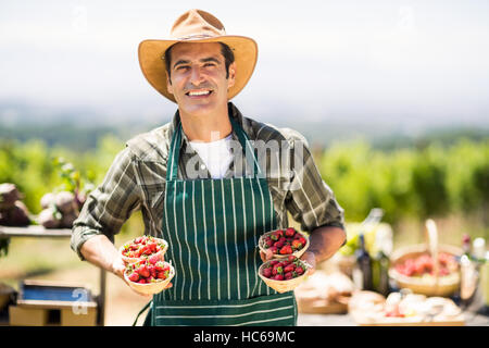 Portrait of a smiling farmer holding bols de fraises Banque D'Images