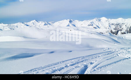 Les pistes de ski sur la neige fraîche dans les montagnes avec des sommets alpins dans l'arrière-plan. Paysage hiver enneigées. Banque D'Images