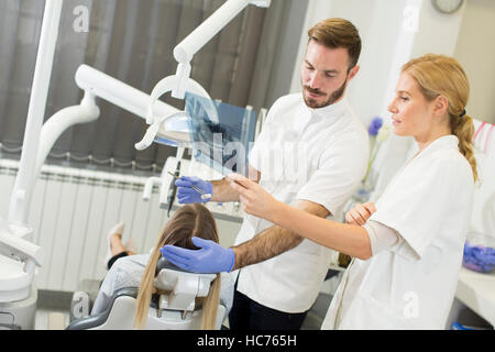 Femme dentiste spécialiste examine une radiographie de la dent en arrière-plan alors que la femme a dentiste checkup Banque D'Images