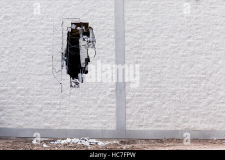 Mur de brique gris d'un grand bâtiment qui est définie pour être démolie a un grand trou en elle. casse briques reposent sur le sol au-dessous de celui-ci et d'armature et d'autres Banque D'Images