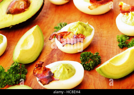 Oeufs farcis à l'avocat et bacon on cutting board Banque D'Images