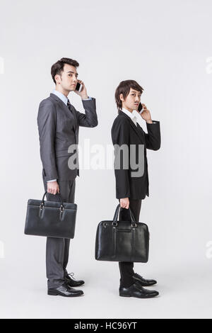 Déguisement femme et homme d'affaires avec elle-même comme porte-documents l'article parler sur les téléphones cellulaires Banque D'Images
