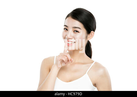 Portrait of young smiling woman en plaçant son doigt sur sa bouche Banque D'Images