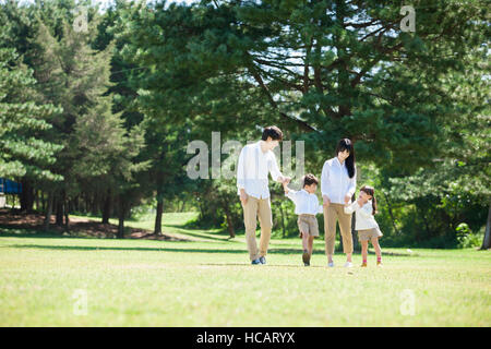 Famille harmonieuse marche main dans la main au parc Banque D'Images