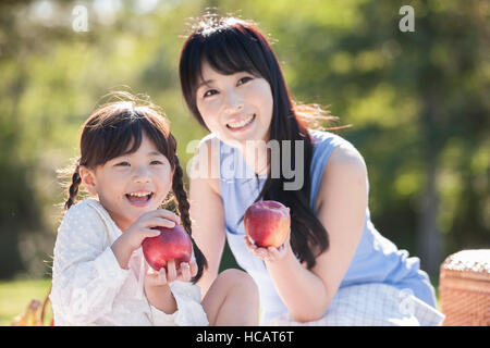 Smiling mother and daughter having picnic aux pommes Banque D'Images