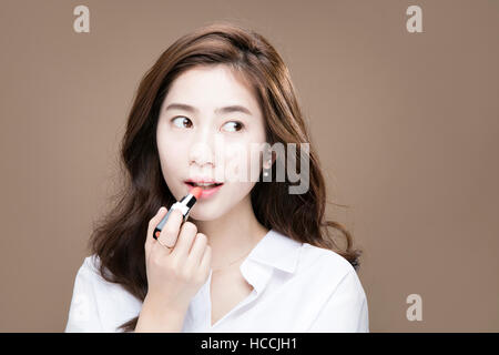 Portrait of young woman putting on lipstick Banque D'Images