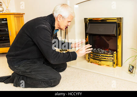 Dao en essayant de garder au chaud les mains de réchauffement près d'un feu en gardant les factures n'ont pas les moyens de chauffage des factures d'énergie gaz UK Angleterre Banque D'Images