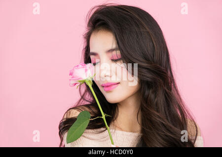 Portrait de jeune femme avec rose rose fermer les yeux Banque D'Images