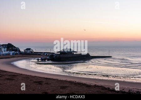 Aube du ciel brisant sur la mer à Broadstairs avec le port et la plage à l'avant-plan. Ciel clair avec couche de nuages sur l'horizon. Mer calme. Banque D'Images