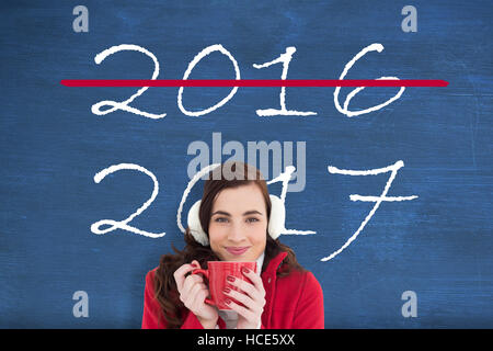 Image composite de femme dans des vêtements d'hiver bénéficiant d'une boisson chaude Banque D'Images