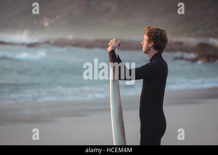 Man wearing wetsuit standing on beach Banque D'Images