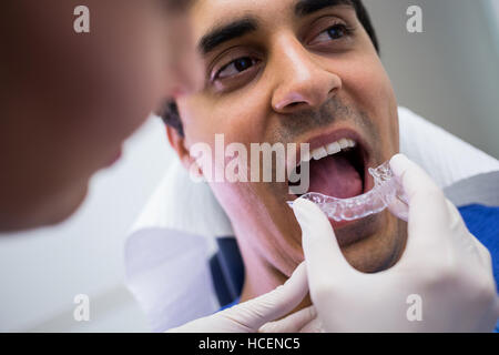 Dentiste aide un patient à porter des croisillons invisibles Banque D'Images