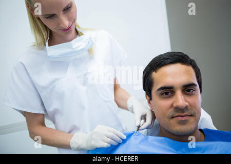 Dentiste aide un patient à porter un tablier dentaire Banque D'Images