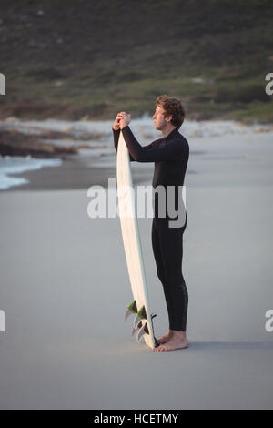 Man wearing wetsuit standing on beach Banque D'Images