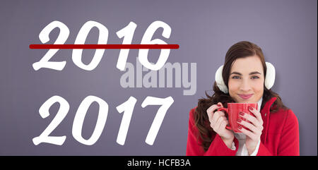 Image composite de femme dans des vêtements d'hiver bénéficiant d'une boisson chaude Banque D'Images