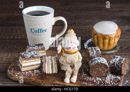 Les différents gâteaux, toy snowman et café sur une surface en bois. Banque D'Images