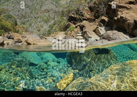 Sur et sous l'eau dans la rivière avec des pierres sur le lit sous l'eau et une pile de cailloux au-dessus de la surface, Dumbea, Nouvelle Calédonie Banque D'Images