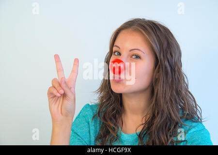 Portrait of young woman wearing clown nose et l'expression de victoire. Voir de très près. Banque D'Images