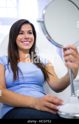 Patient sourire en regardant dans le miroir à la clinique Banque D'Images