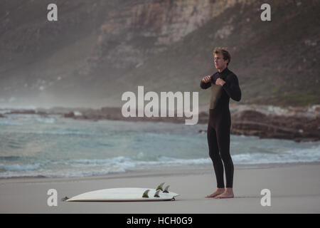 Man wearing wetsuit standing on beach Banque D'Images