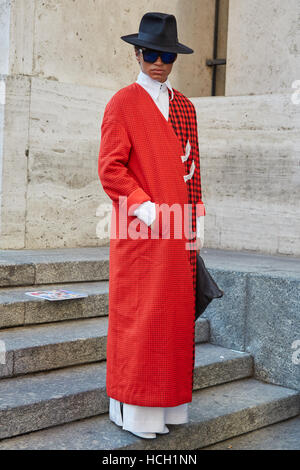 Homme avec manteau rouge et noir hat avant de Salvatore Ferragamo fashion show, Milan Fashion Week street style le 25 septembre 2016. Banque D'Images