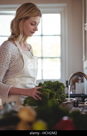 Belle femme lave le brocoli sous l'évier dans la cuisine Banque D'Images