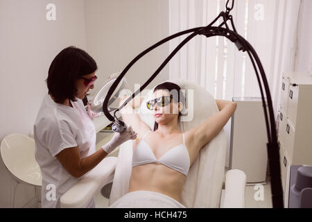 Médecin effectuant l'enlèvement de cheveux de laser sur la peau du patient de sexe féminin Banque D'Images