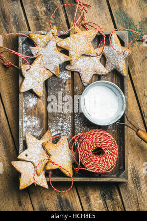 Gingerbread cookies en forme d'étoile de Noël avec du sucre en poudre et la décoration de corde en plateau en bois rustique sur arrière-plan, Vue de dessus, l'espace de copie, vertical Banque D'Images