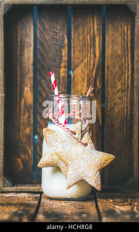 Bouteille de lait et de fête de Noël gingerbread cookies en forme d'étoile avec décor sur fond de bois de corde, copiez l'espace, composition verticale Banque D'Images