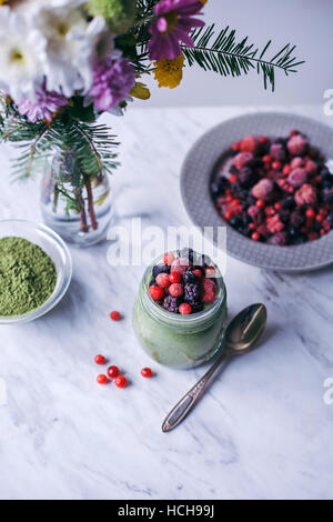 Thé vert matcha chia pudding garni de petits fruits congelés dans un bocal en verre Banque D'Images