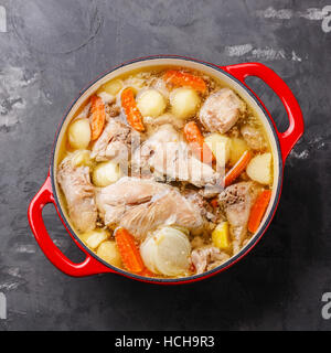 Compotée de Lapin aux pommes de terre et la carotte en fonte pot sur fond de béton Banque D'Images