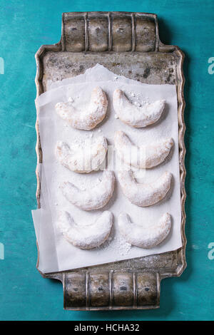 Des cookies noix de Noël avec du sucre en poudre sur crescent vintage metal plateau avec du papier sulfurisé comme sapin sur turquoise texture boisée backgroun Banque D'Images
