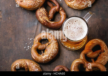 Verre de bière blonde avec plus de bretzels salés traditionnels en bois ancien arrière-plan. Vue de dessus avec l'espace pour le texte. Thème de l'Oktoberfest Banque D'Images