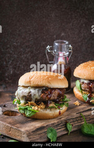 Deux hamburgers avec escalope de bœuf, oignon frit, épinards, sauce ketchup et fromage bleu traditionnel de buns, servi sur planche en bois plus da Banque D'Images