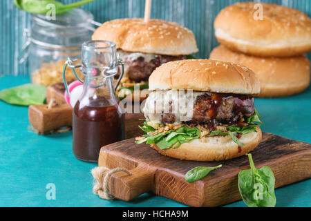 Deux hamburgers avec escalope de bœuf, oignon frit, épinards, sauce ketchup et fromage bleu traditionnel de buns, servi sur planche en bois plus de br Banque D'Images