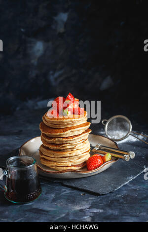 Pile de gluten de la farine d'avoine crêpes servi avec des morceaux de fraises et le sirop d'érable Banque D'Images