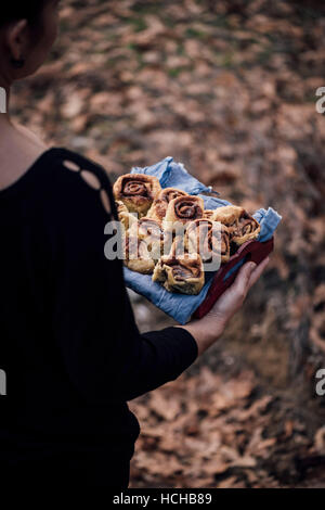 Une femme tenant un plateau plein de cannelle dans la nature des feuilles sèches. Banque D'Images